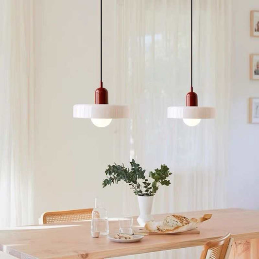 Modern glass pendant lighting with customizable hanging length over a wooden dining table in a bright room
