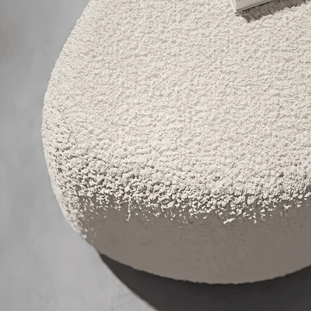 Beige pouf ottoman with plush lambswool upholstery and modern minimalist design