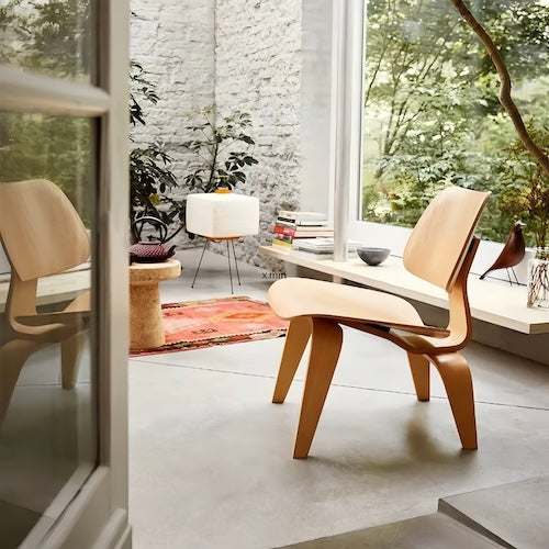 Timeless molded plywood Lounge Wood Chair in natural log finish in modern airy room with plants and books
