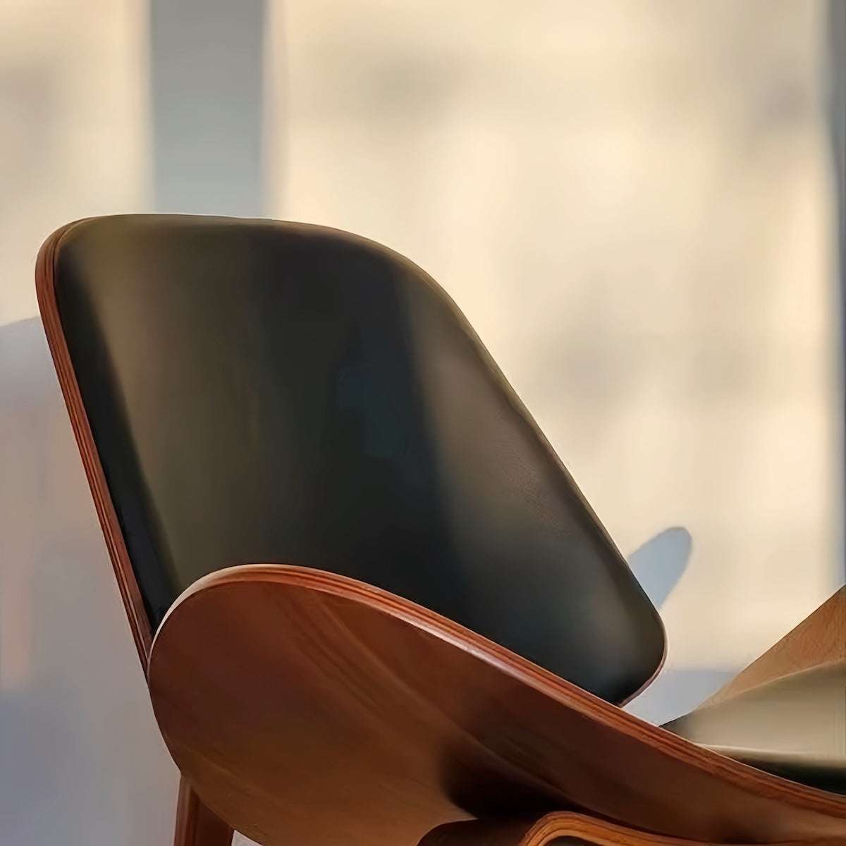 Sleek black and walnut Shell Chair with genuine leather upholstery and elegant design.