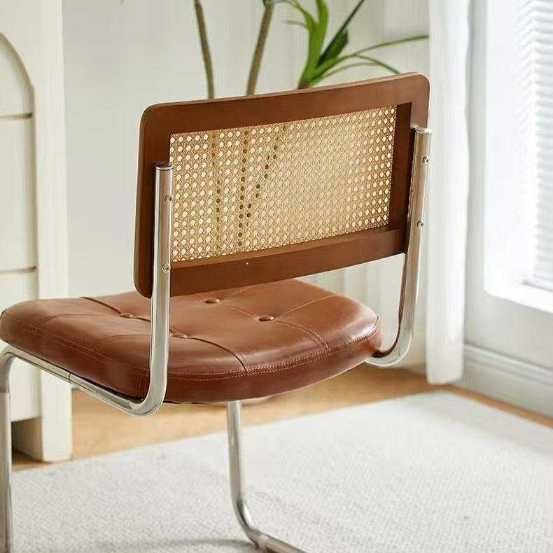 Modern minimalist bedroom chair with stainless steel frame, rattan backrest, and microfiber leather seat