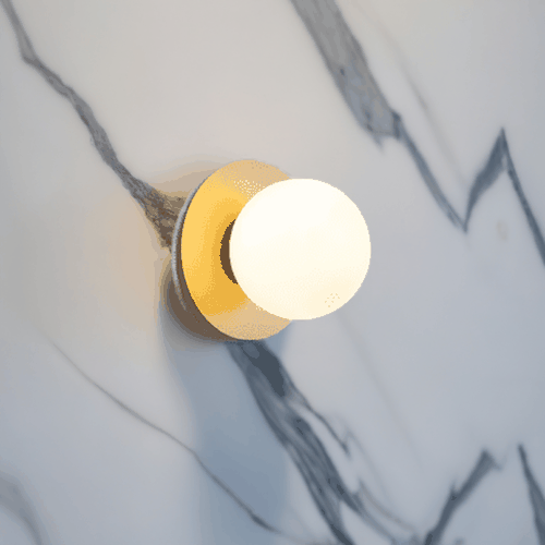 Modern round wall sconce with frosted glass and warm white LED light mounted on marble wall