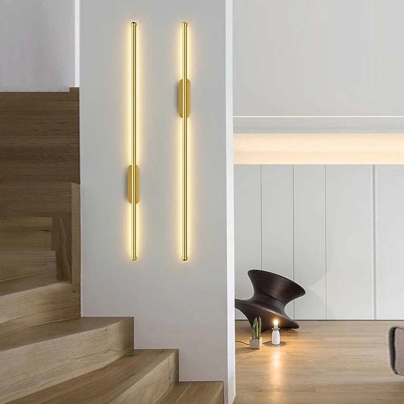 Sleek modern wall lights in black and gold illuminating a stylish living room staircase wall