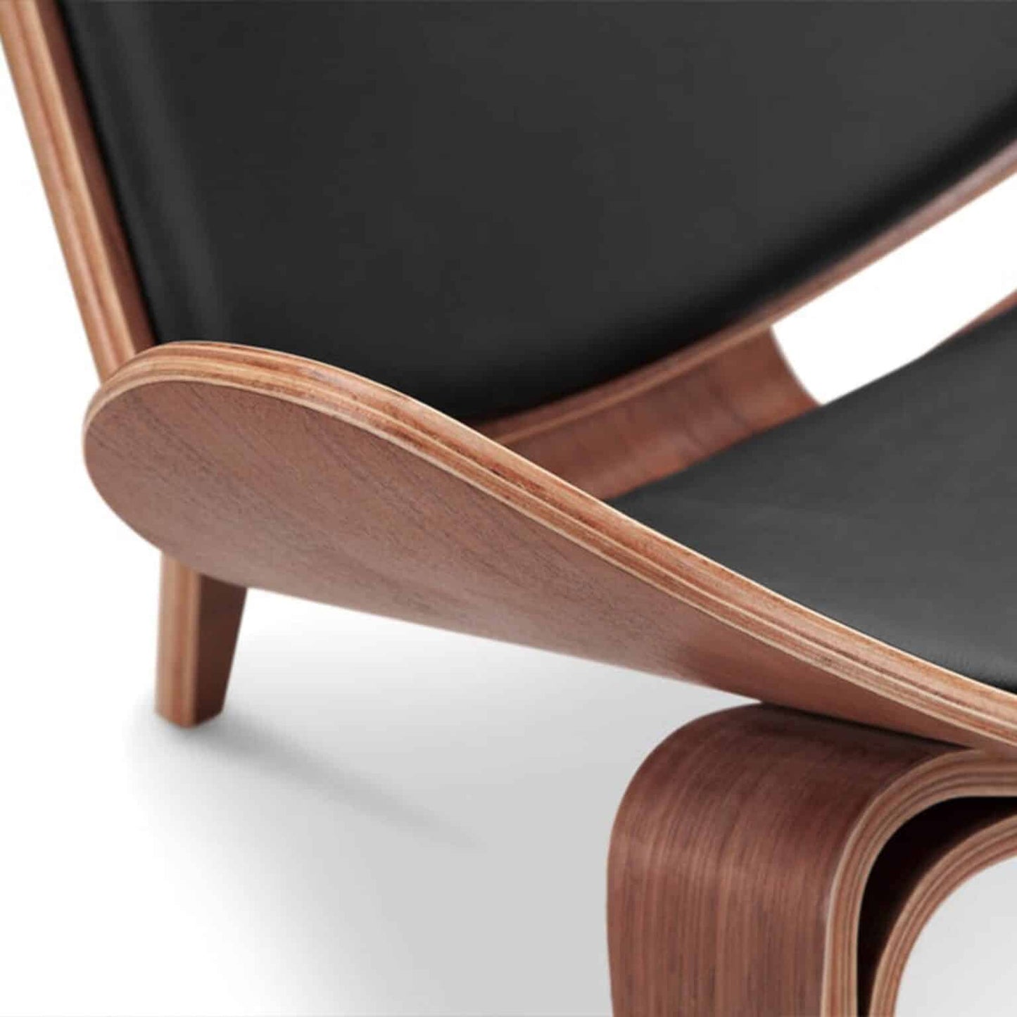 Shell Chair with walnut wood frame and black leather upholstery, showcasing mid-century design and craftsmanship.