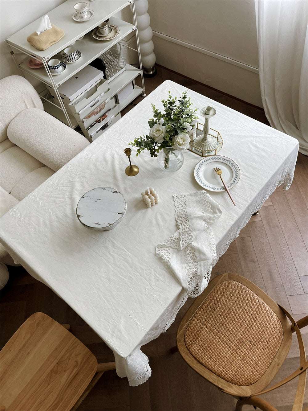 Handmade white cotton tablecloth with embroidered patterns on rectangular dining table in elegant room setting
