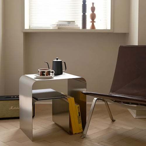Minimalist stainless steel metal side table with elegant curved design in modern living room setting