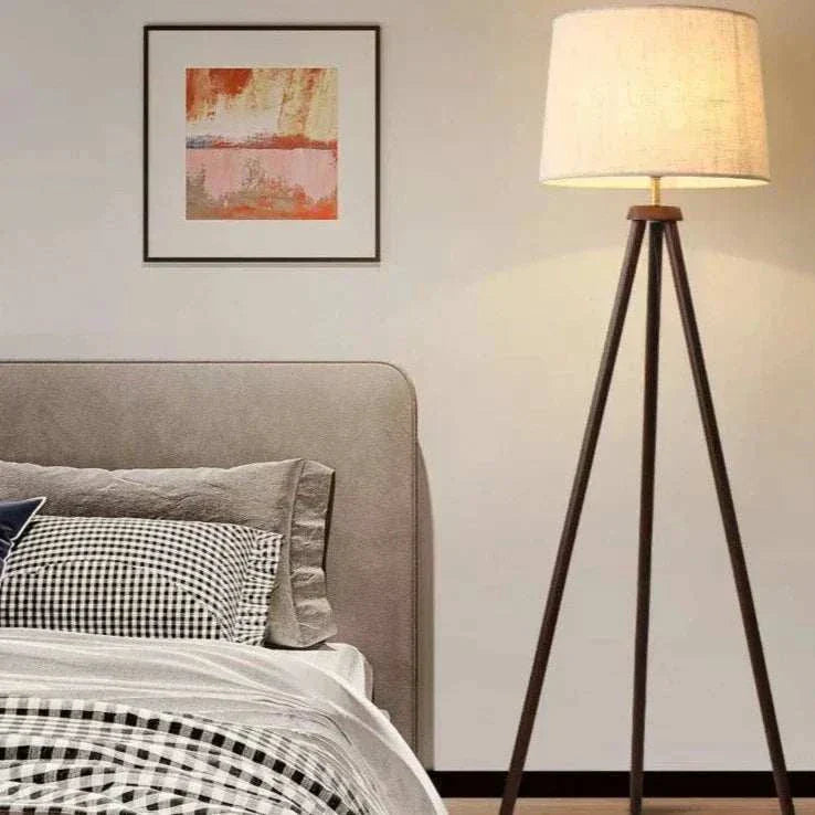 Mid Century Floor Lamp with wooden tripod base and fabric shade in bedroom setting