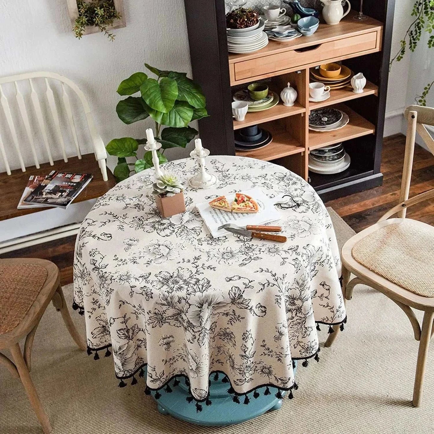Round tablecloth with black rose floral pattern on cream fabric in cozy dining setting