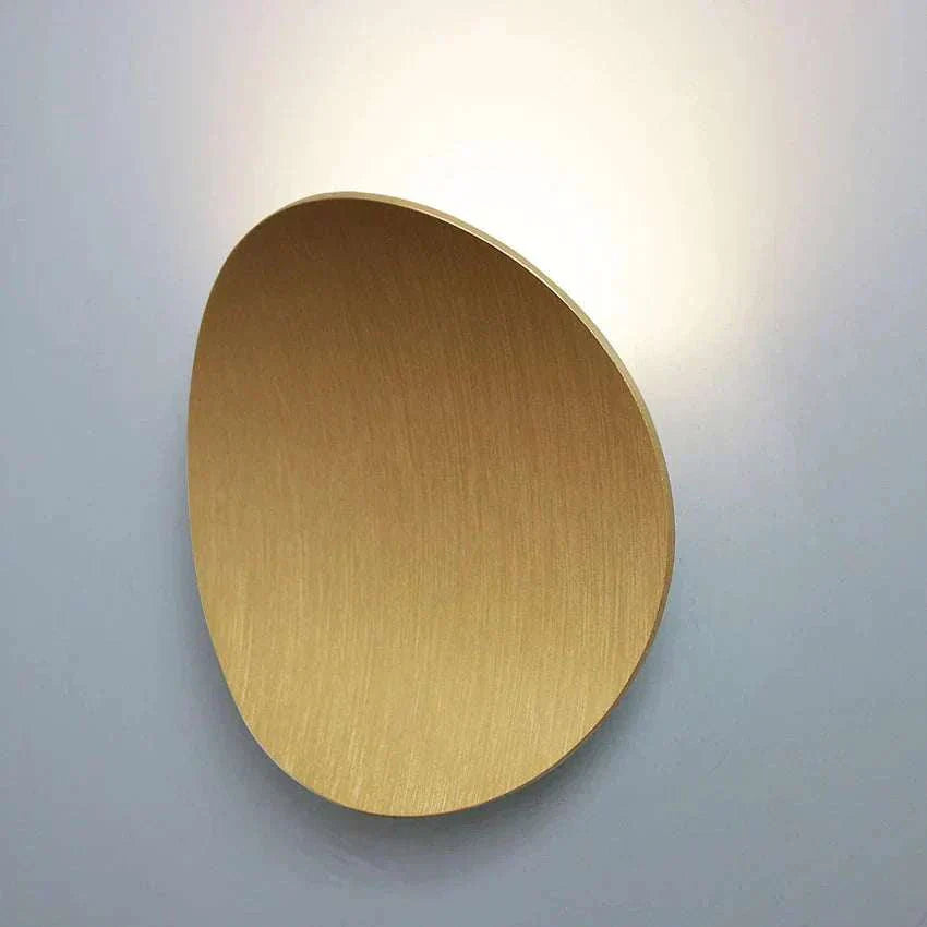 modern gold LED wall light with oval seashell design and aluminum finish illuminating background