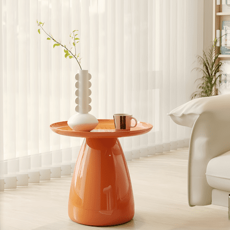 Orange small side table made of PVC with modern round design in a bright living room setting