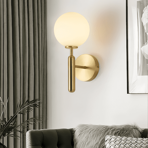 single head glass wall sconce with brass metal base and warm white LED globe light in modern living room setting