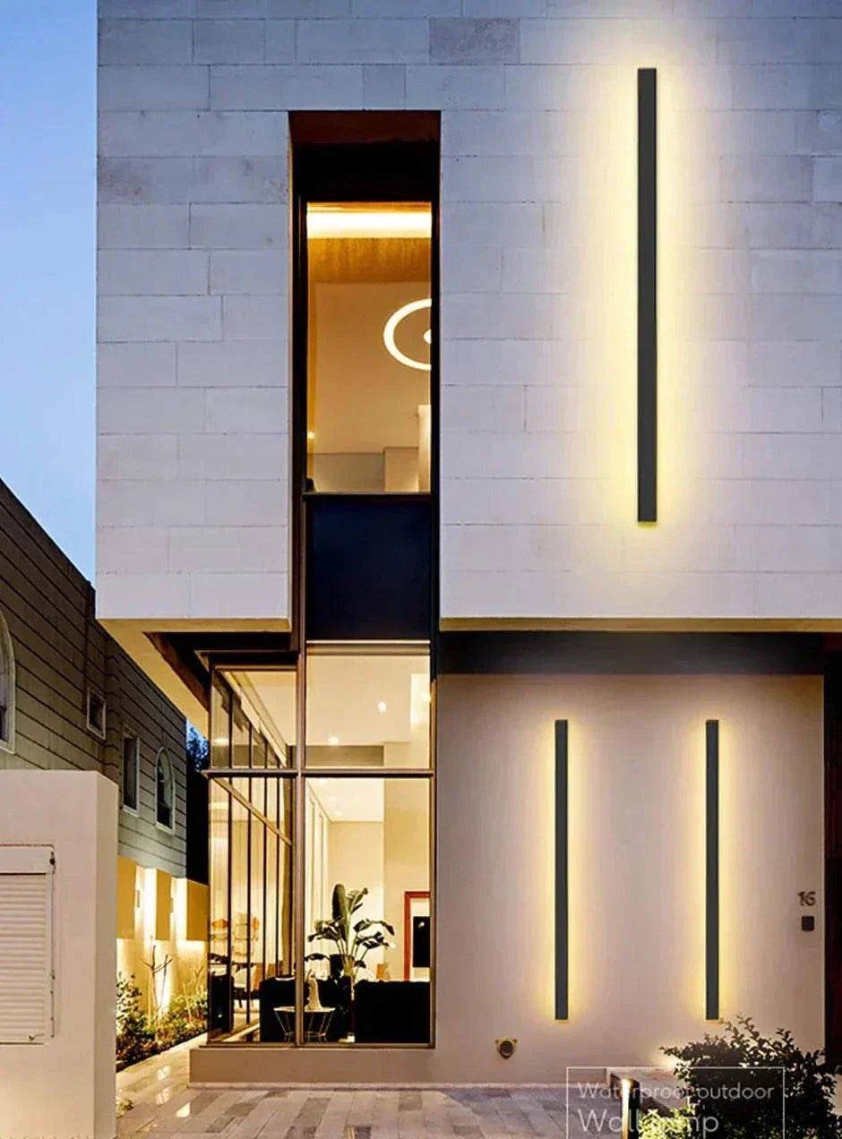 Modern waterproof IP65 outdoor wall light mounted on white exterior wall illuminating front entrance at night