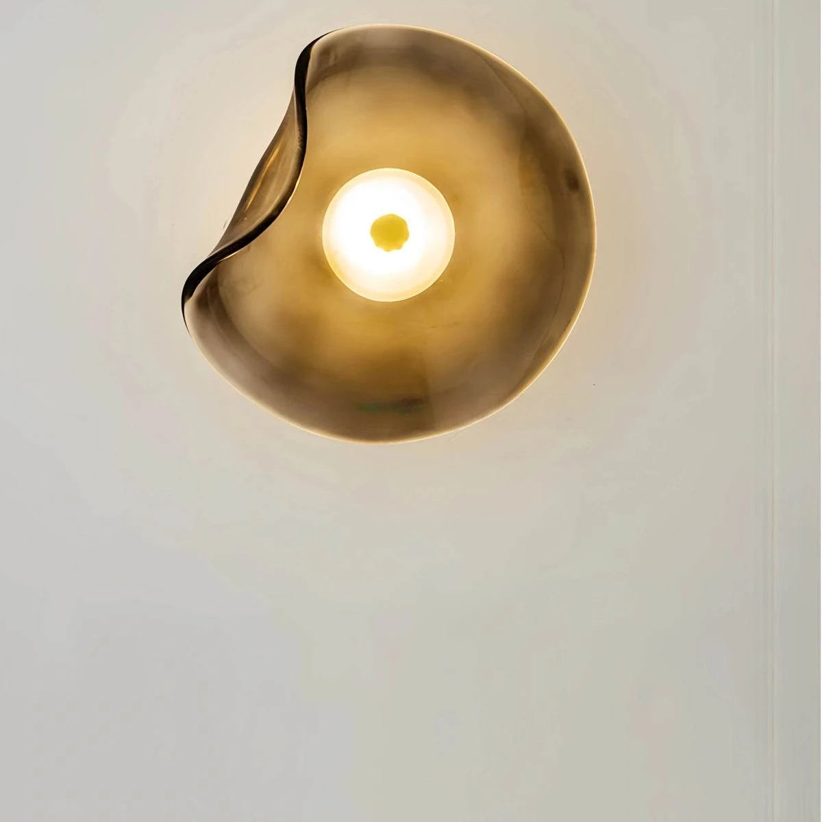 Round minimalist wall sconce with wrought iron frame and translucent glass shade in smoke color illuminating bedroom wall