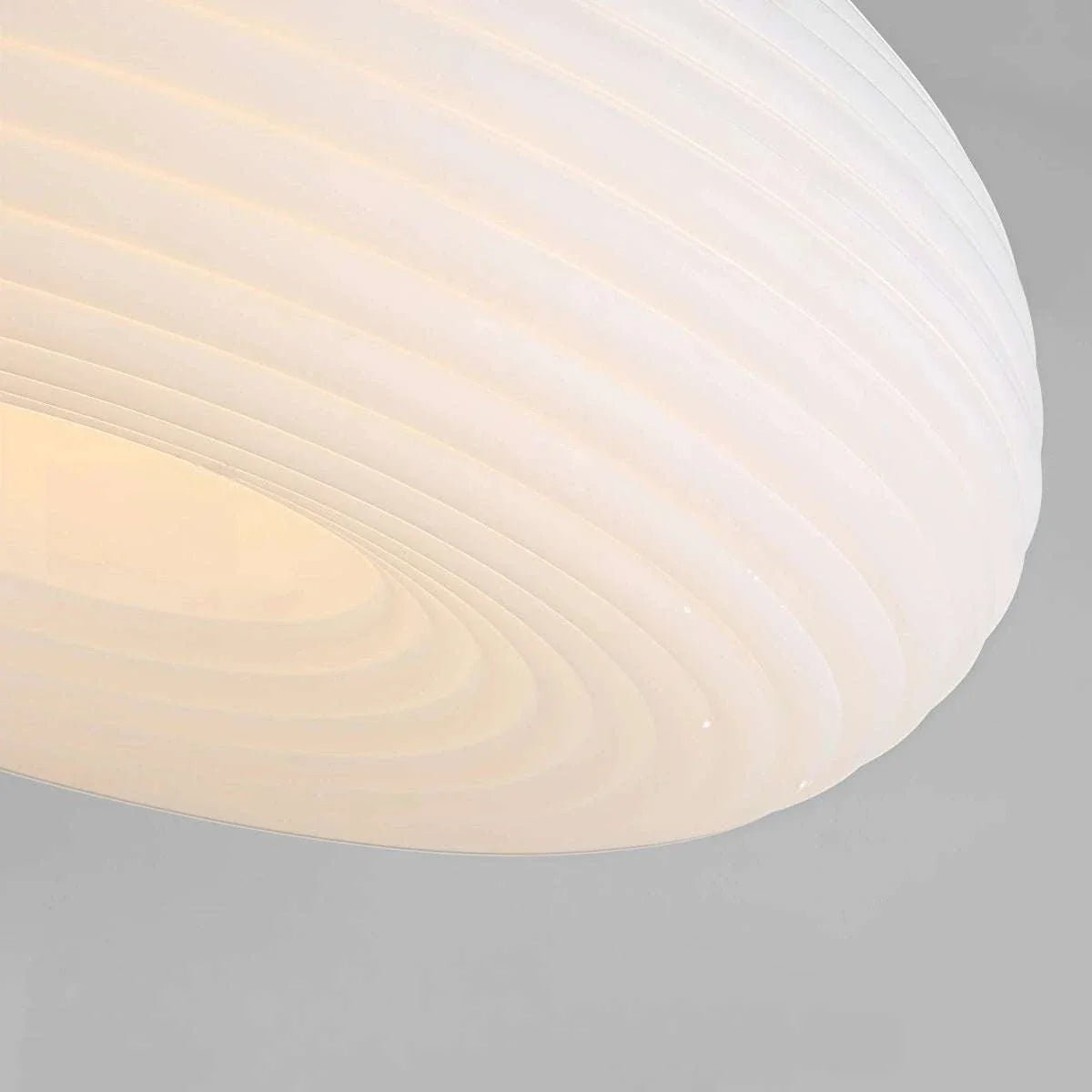 Minimalist Nordic pendant light with oval ribbed lampshade hanging over dining table