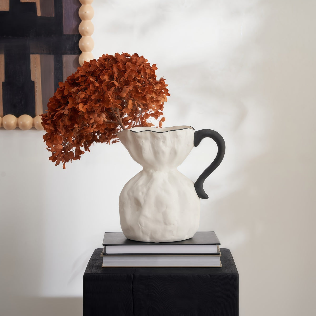 Irregular Ceramic Vase in white ceramic with a sculpted irregular shape, black handle and dried flowers
