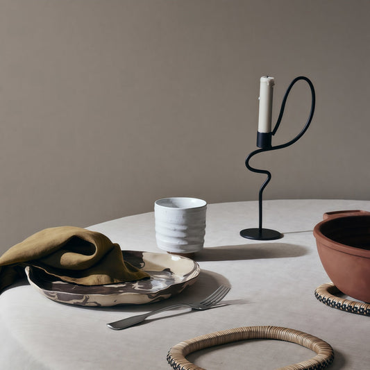 Dancer-Themed Floor-Standing Candle Holder in black metal, with a looping sculptural stem, round base and white candle.