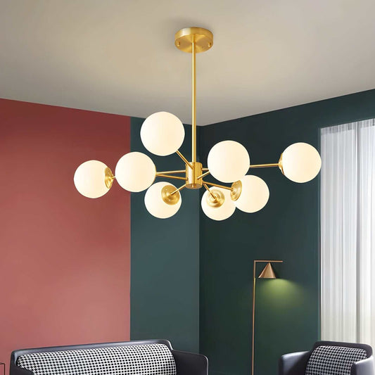 Modern gold 8-light globe pendant light chandelier with frosted glass shades in a stylish living room setting