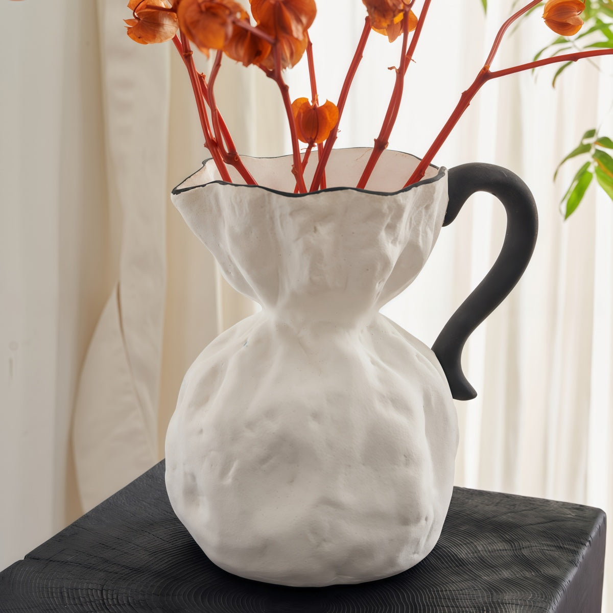 Irregular Ceramic Vase in textured matte white ceramic, featuring a rounded body, flared rim and black curved handle
