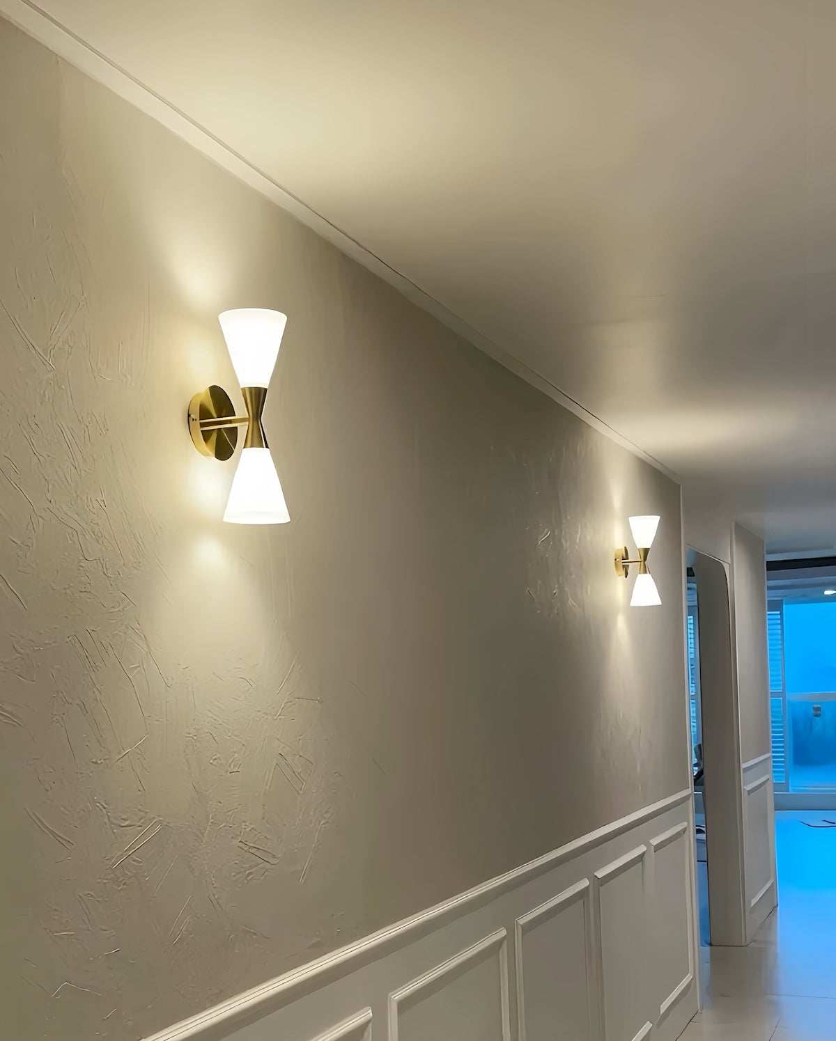 Nordic modern hourglass wall sconce with frosted glass and chrome finish lighting a hallway wall