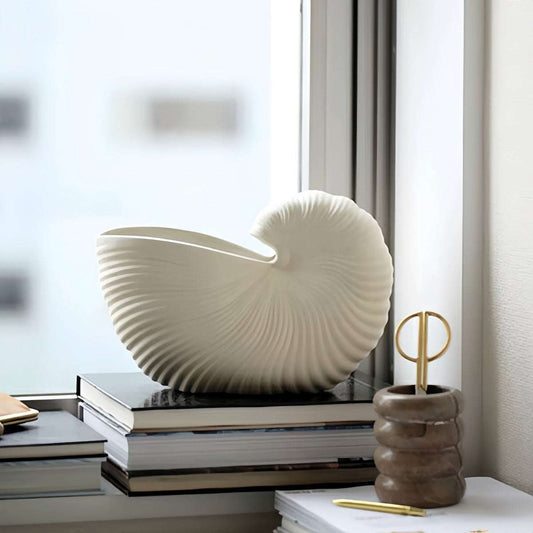 Nordic style ceramic seashell vase on books by window in modern home decor