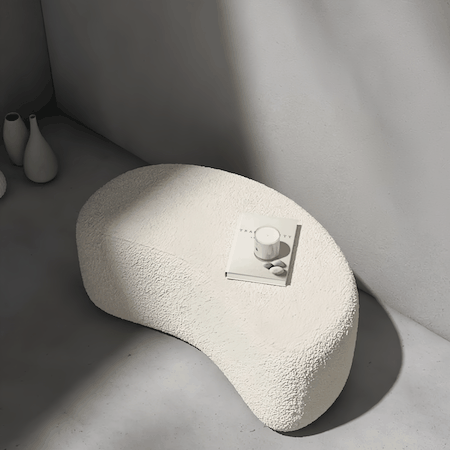 Beige lambswool pouf ottoman with minimalist curved design and solid wood frame in modern living space