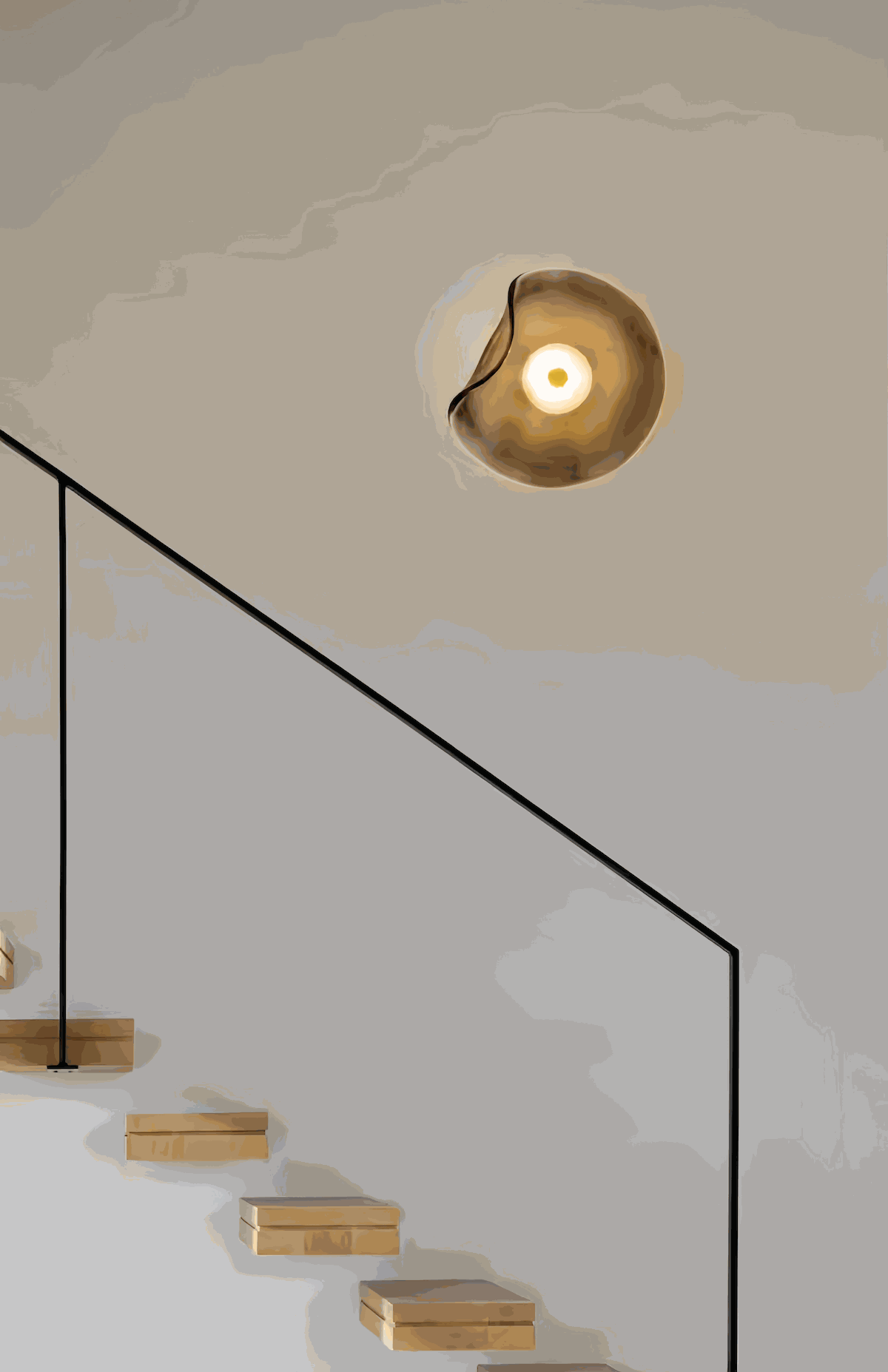 Round minimalist wall sconce with wrought iron frame and warm LED light in a bedroom setting