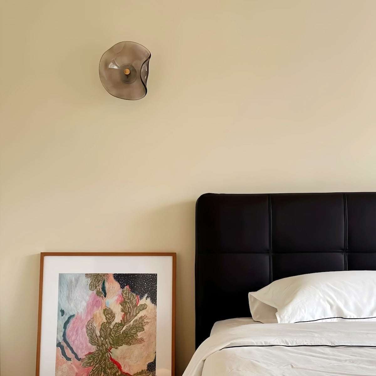 Round minimalist wall sconce with wrought iron frame and warm LED light in smoke or amber glass
