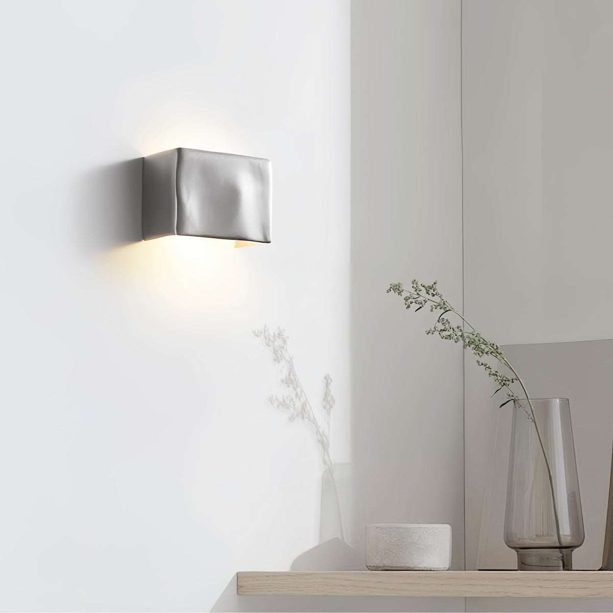 Scape Wall Light modern aluminum outdoor sconce with warm white illumination on white wall above wooden shelf with minimal decor