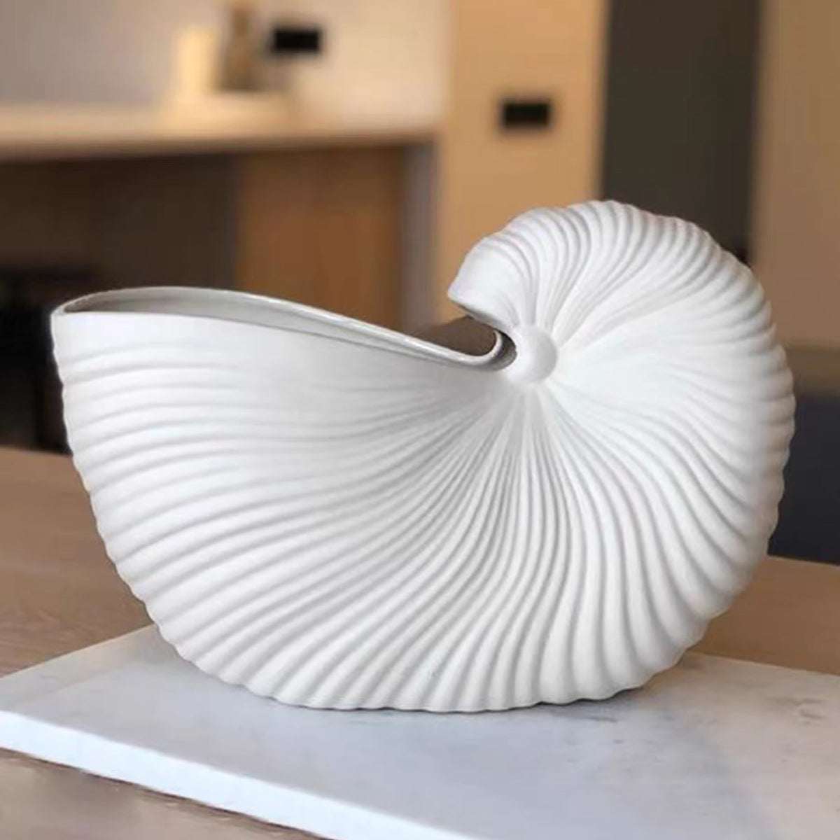 White ceramic seashell vase with matte finish and Nordic design on table