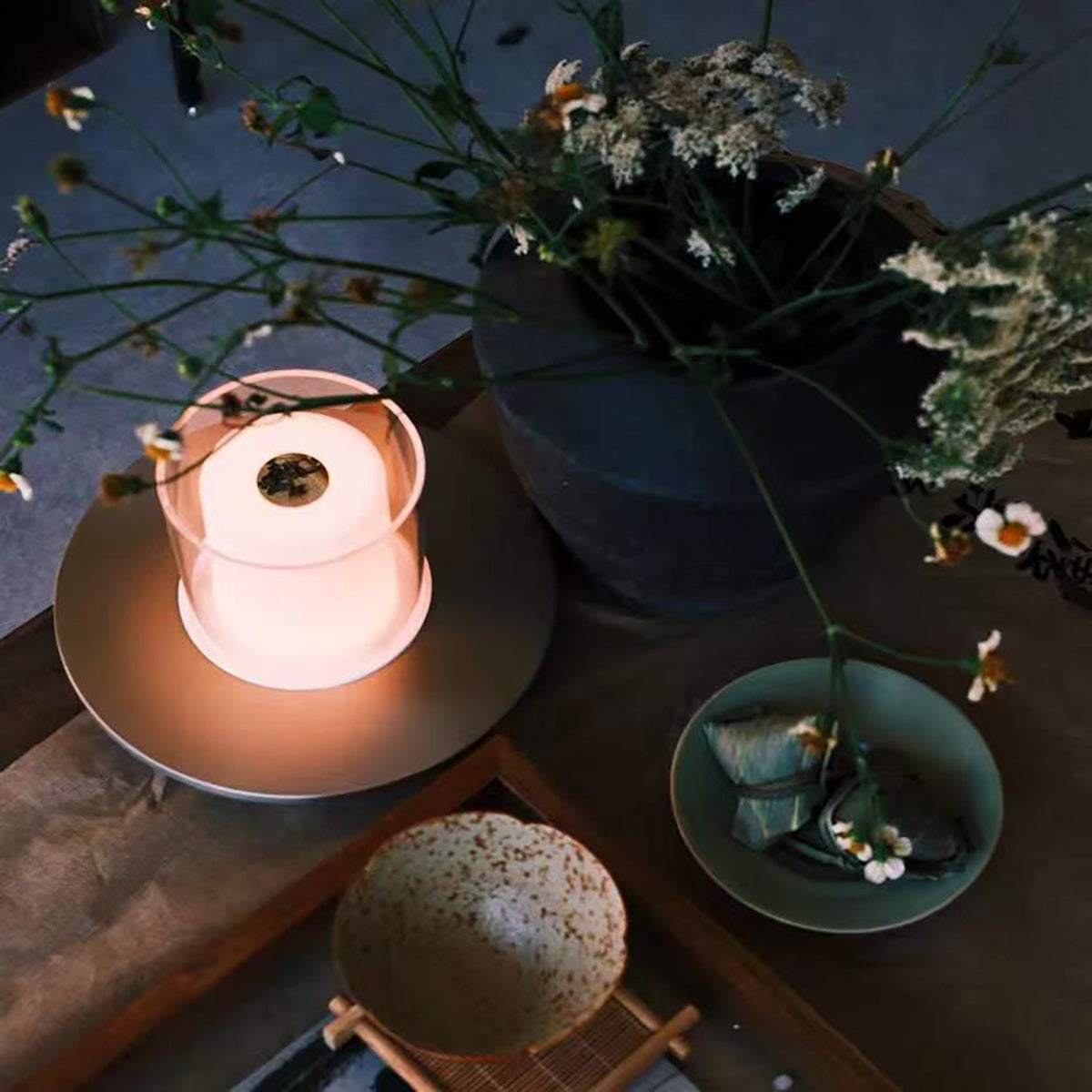 Rechargeable ambience night lamp with warm LED glow on dining table with plants and bowls