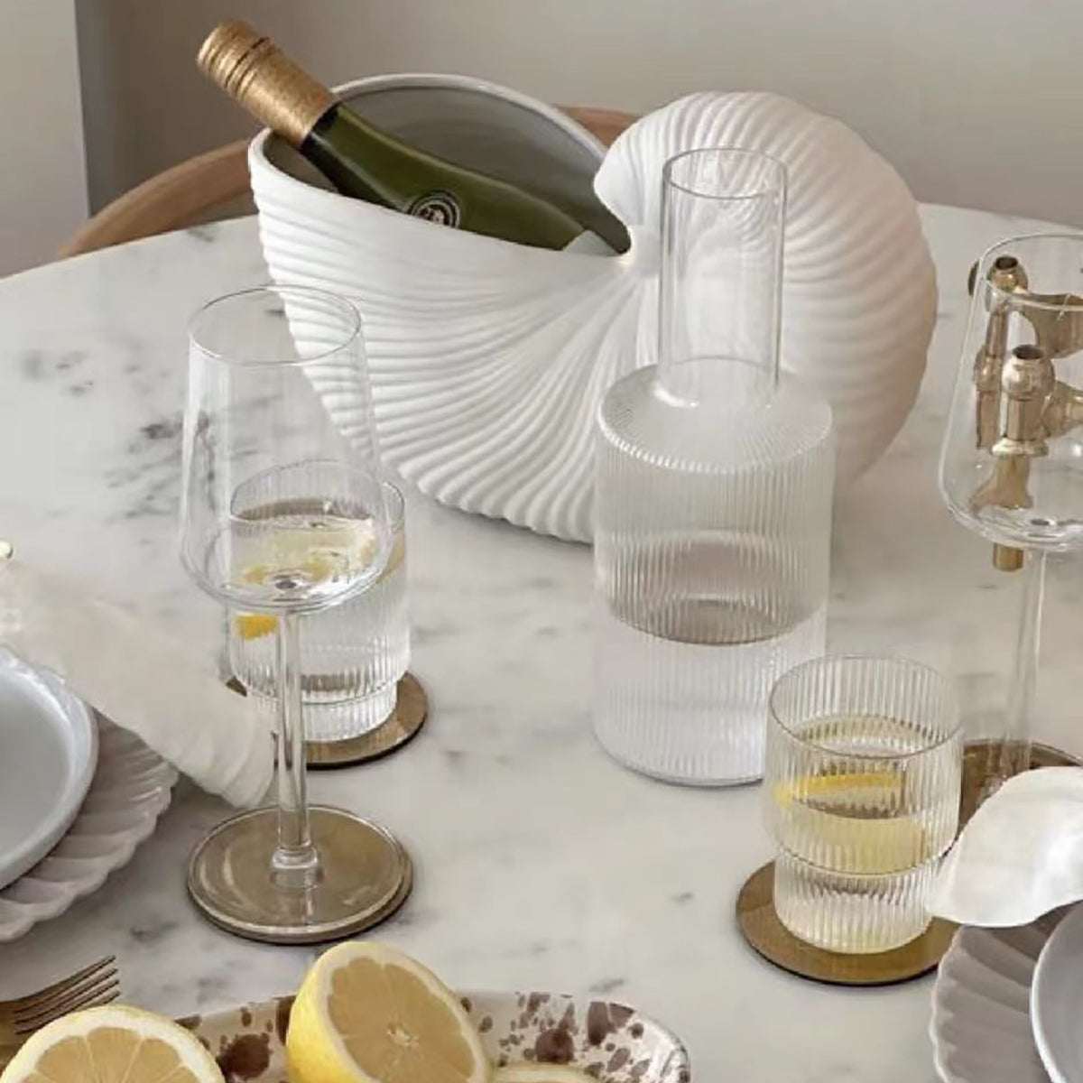 Nordic style ceramic seashell vase on marble table with wine bottle and glassware