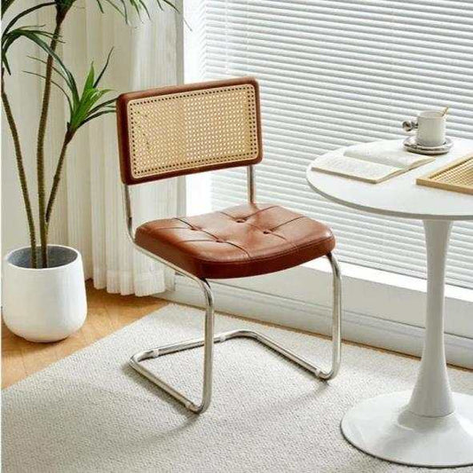 modern minimalist bedroom chair with stainless steel frame, rattan backrest, and microfiber leather seat in cozy bedroom setting