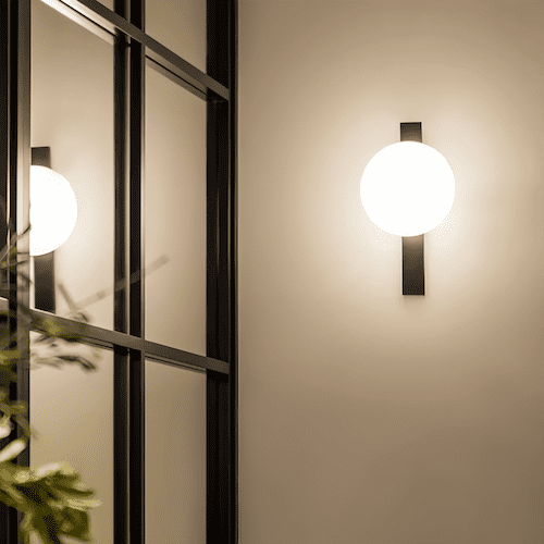Minimalist LED wall lamp with round white globe and black vertical mount illuminating modern interior space
