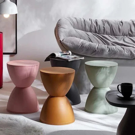 Set of minimalist modern dressing table stools in multiple colors next to gray sofa and side table