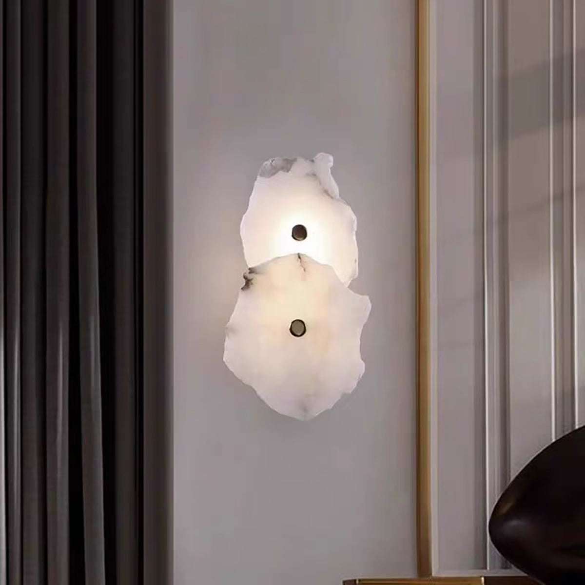 modern marble wall light with two natural stone discs and brass hardware mounted on interior wall
