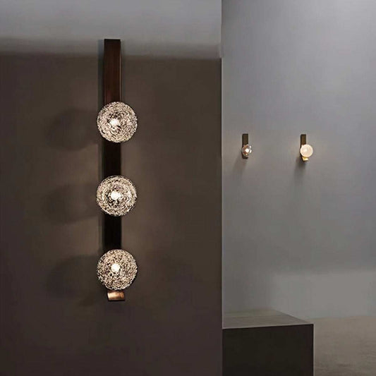 Luxury wall lamp with triple bubble glass lights on iron frame casting warm ambient glow on dark wall