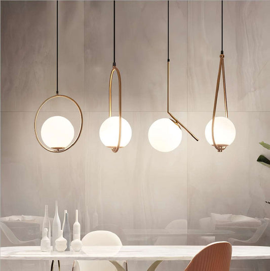 Modern elegant gold pendant light with brushed gold finish and spherical white glass shades hanging above a dining table.
