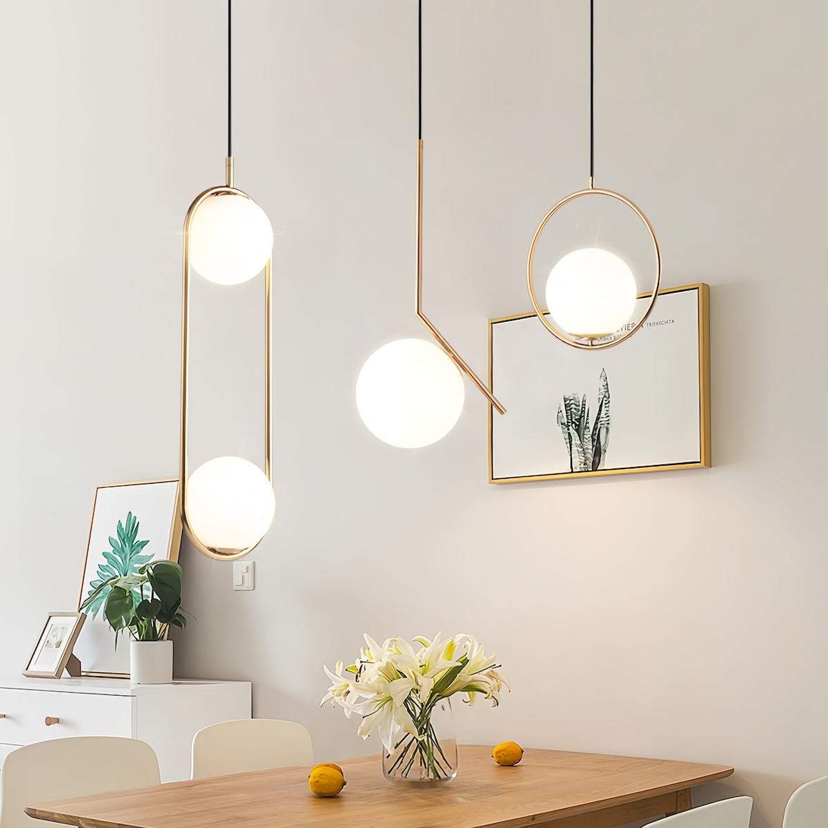 Modern gold pendant light with brushed gold finish and spherical frosted glass shades hanging over a dining table in a minimalist room