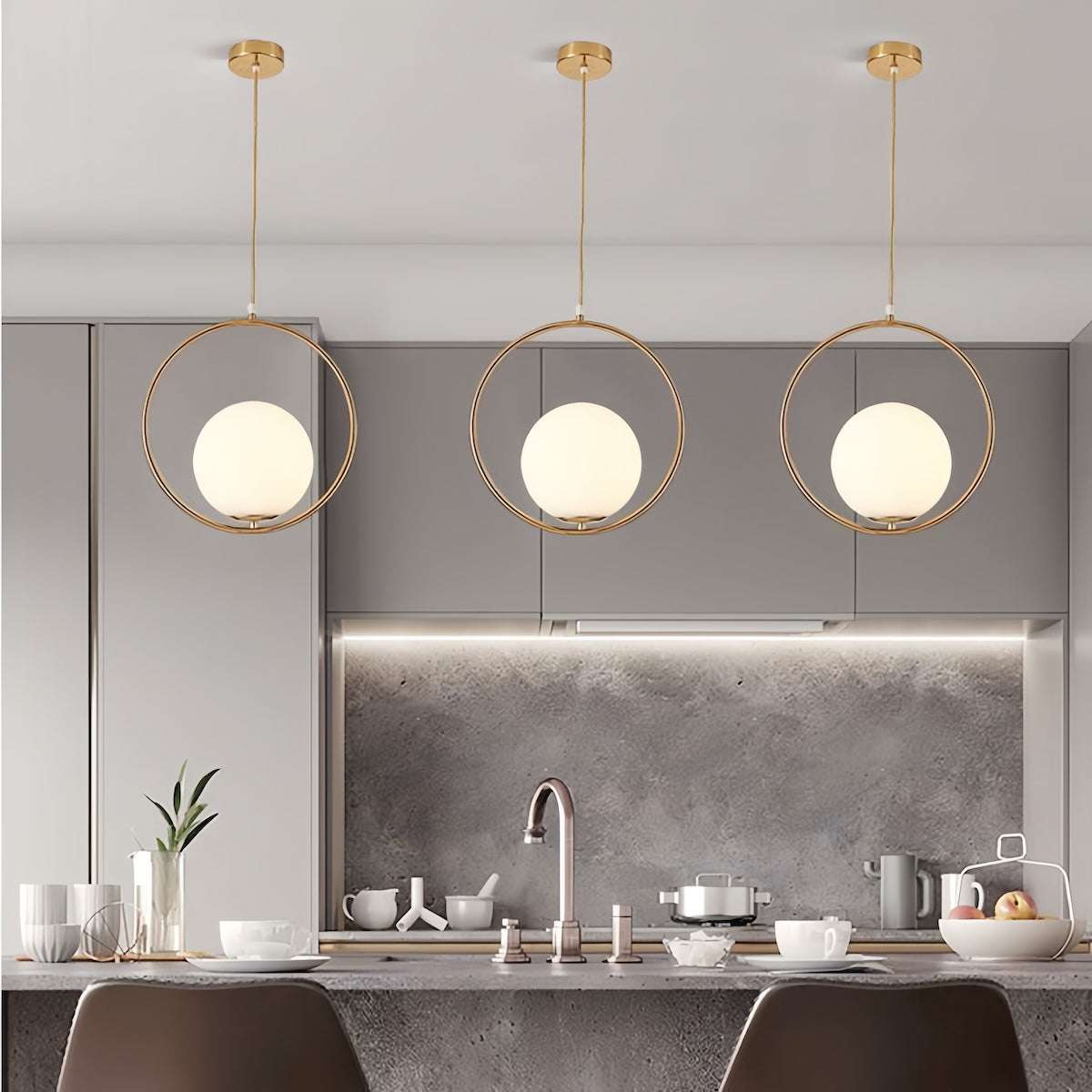 Modern brushed gold pendant light with adjustable hanging length and warm white LED bulbs in a kitchen setting