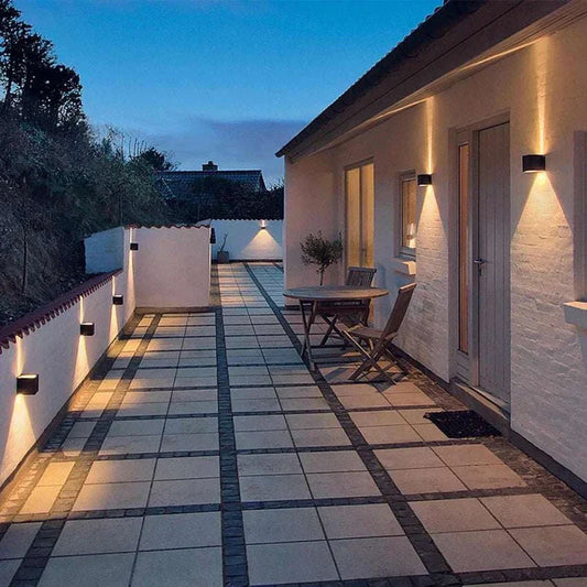 IP65 outdoor LED wall lights illuminating a modern patio and walkway at dusk