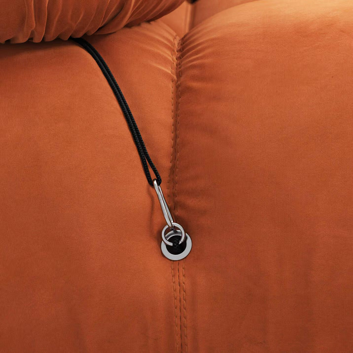 Close-up of an orange jacket with a zipper pull and black cord.