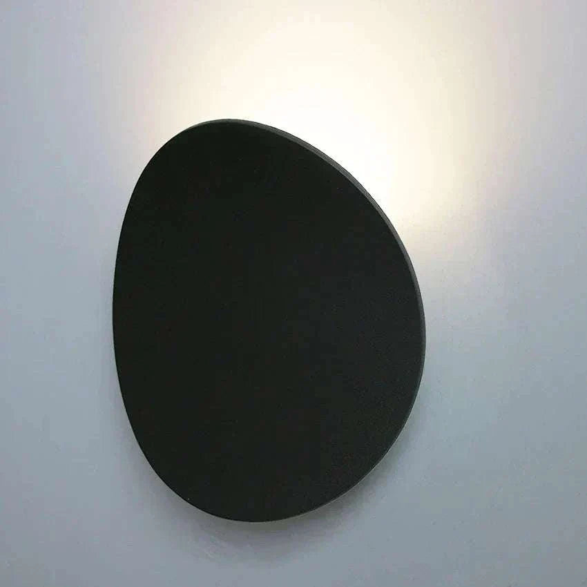 Modern black oval LED wall light with seashell-inspired design illuminating upward