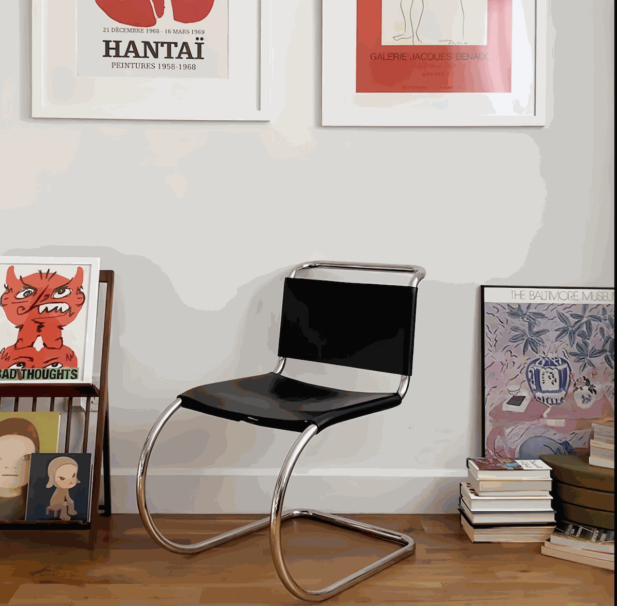 Minimalist stainless steel dining chair with black leather seat and modern cantilever design in stylish home setting