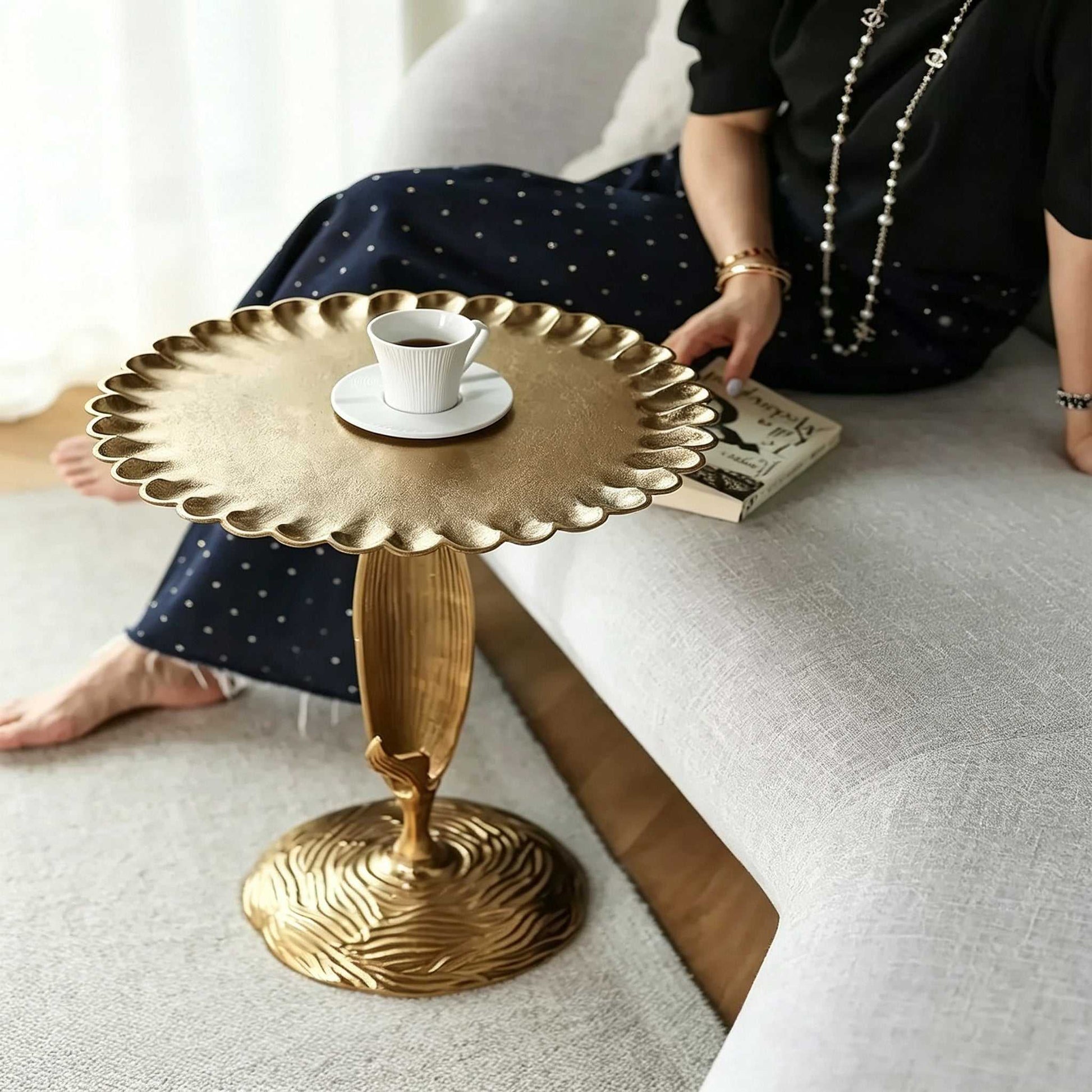 Luxury aluminum sofa side table with scalloped tabletop and sculptural leaf-shaped stem in modern bedroom setting