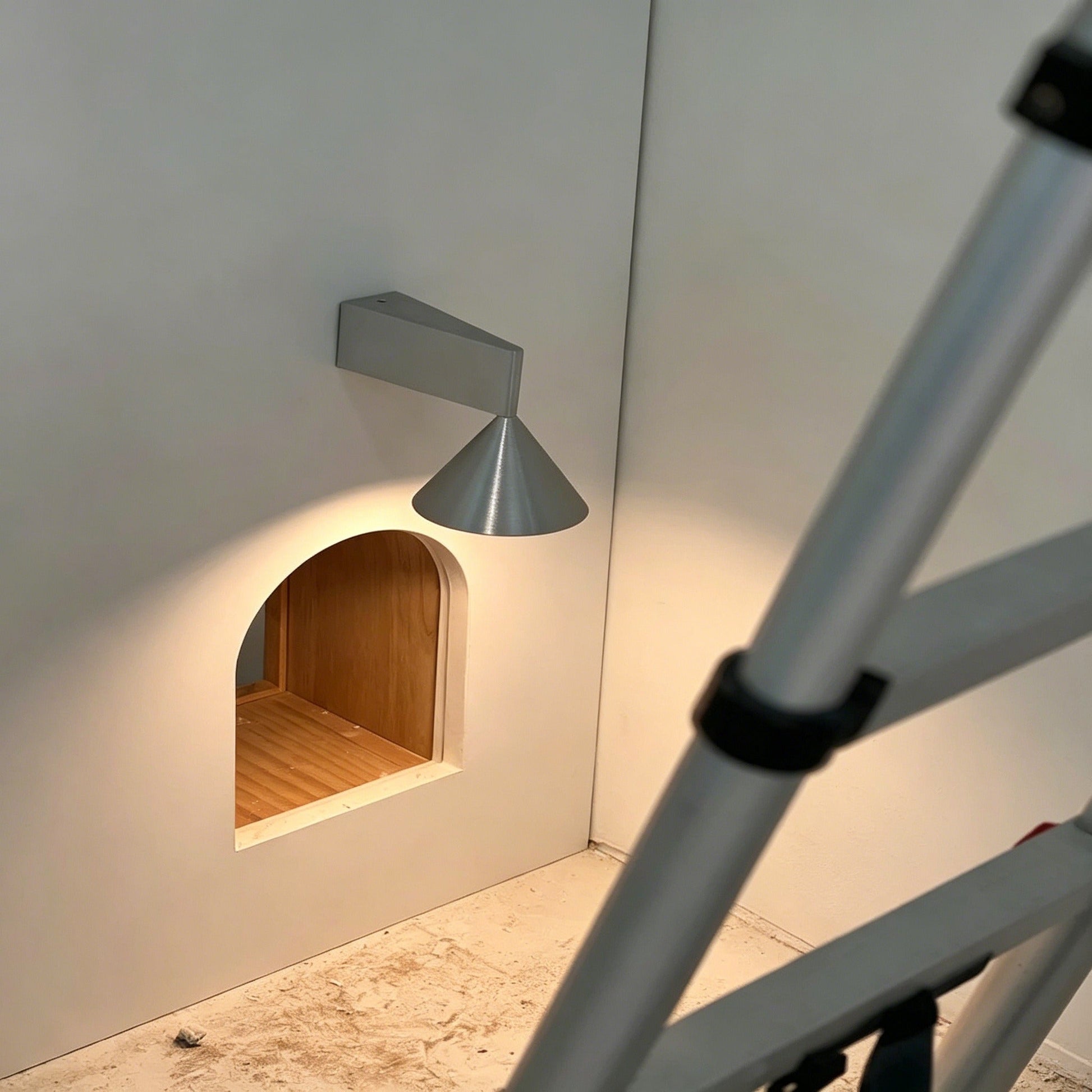 Italian minimalist modern wall sconce with conical shade and brushed anodized finish illuminating hallway