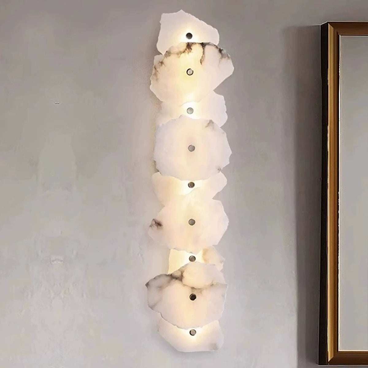 Vertical marble wall light with multiple natural marble discs and warm LED illumination on a modern interior wall