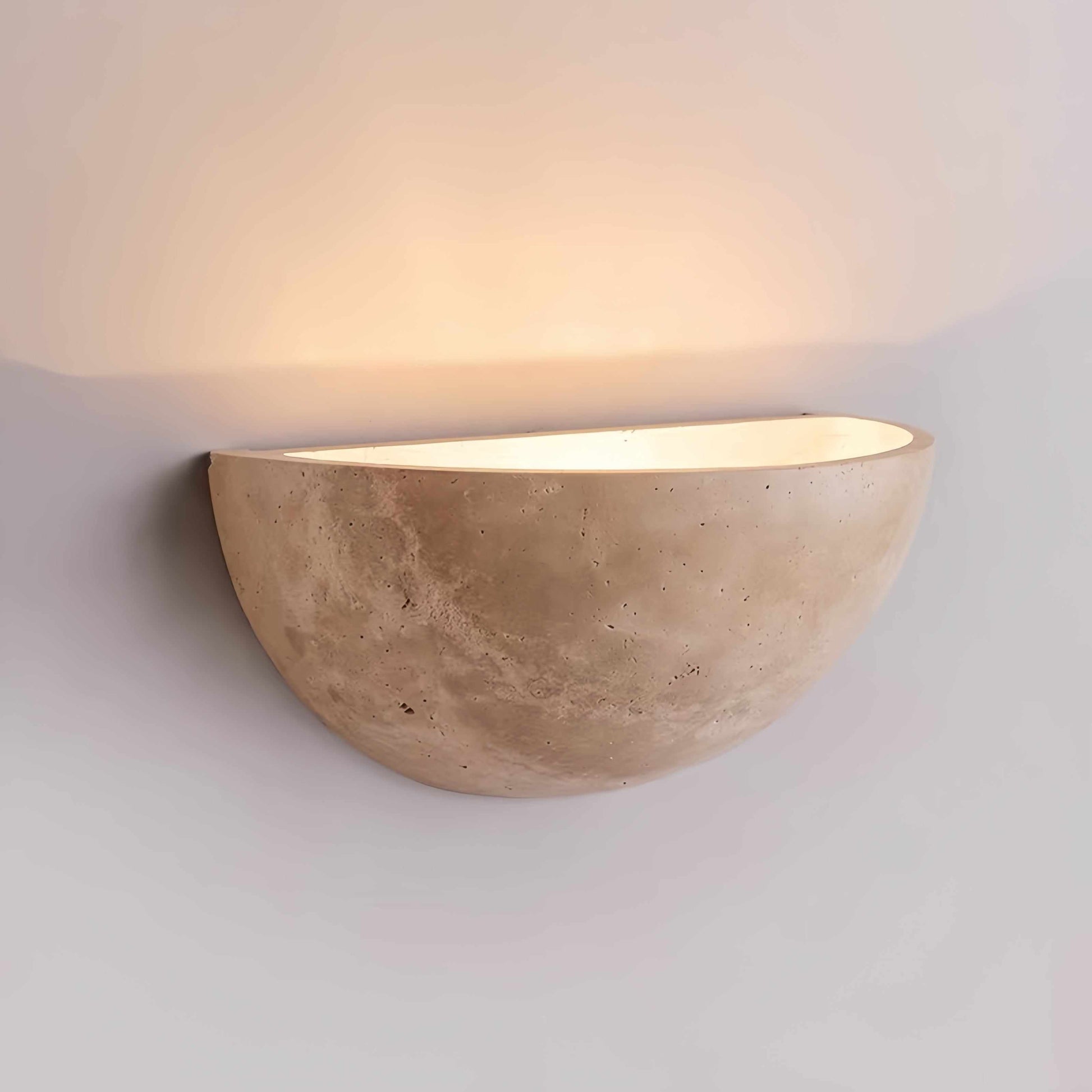 Vintage Wabi-Sabi style wall sconce made of natural off-white travertine casting warm soft light on wall