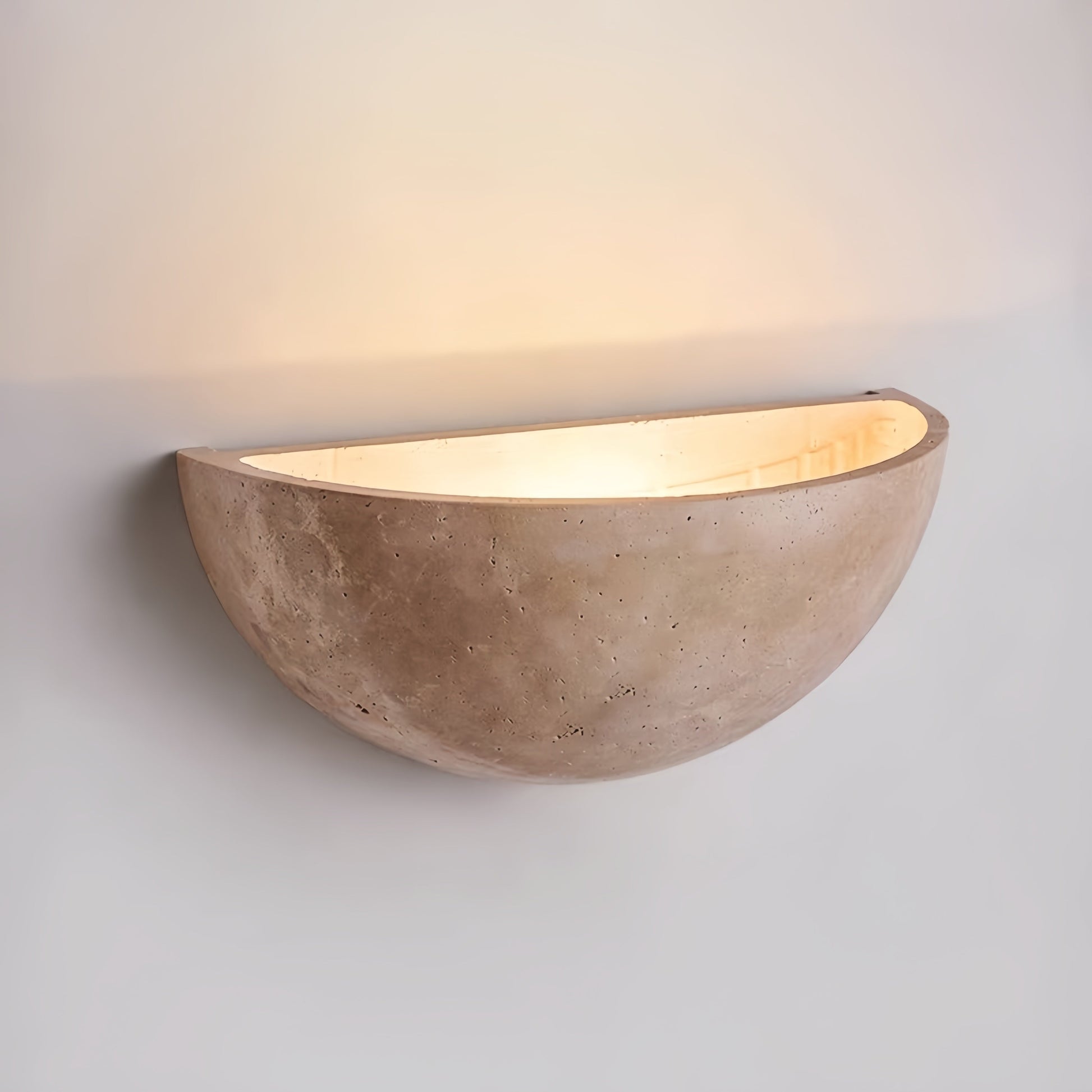Vintage Wabi-Sabi style wall sconce made from natural off-white travertine, hand-polished with seamless design casting soft warm light on the wall.